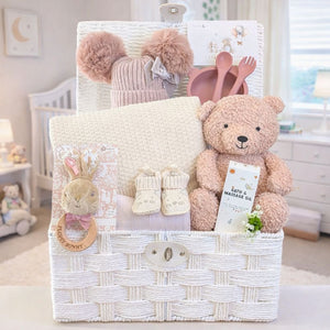 Baby girl gift basket with teddy bear, plush toys and baby items in a nursery baket.