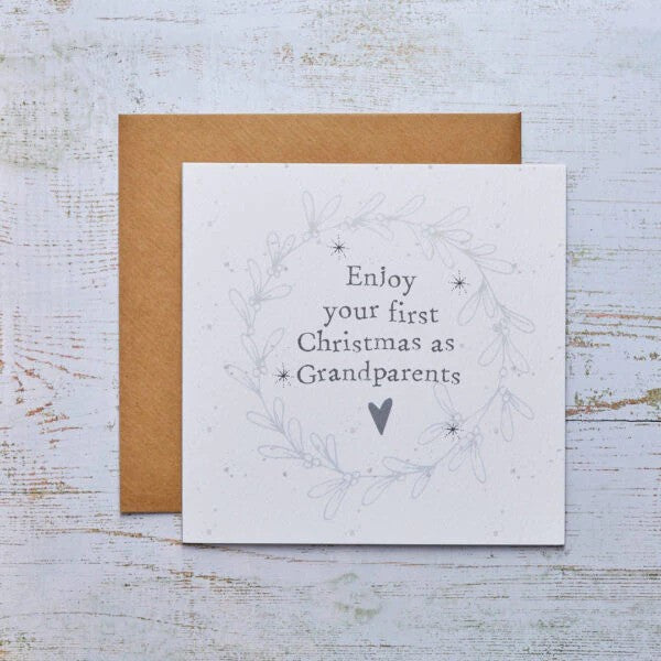 White card with grey holly design and text reading &quot;Enjoy your first Christmas as Grandparents&quot; with a brown envelope.