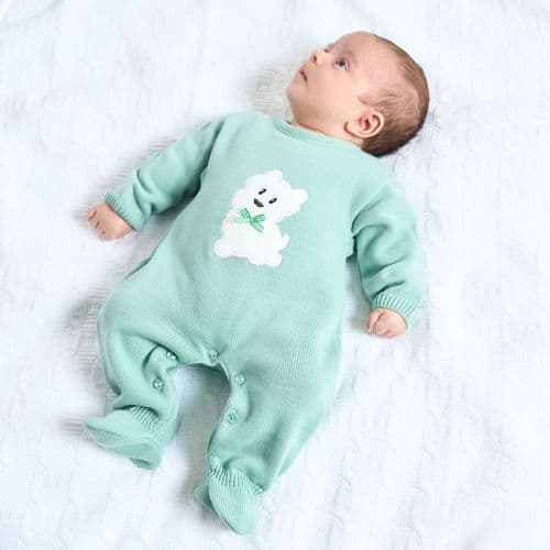 Baby wearing a green knitted onesie with a white Scotty dog applique on the front.