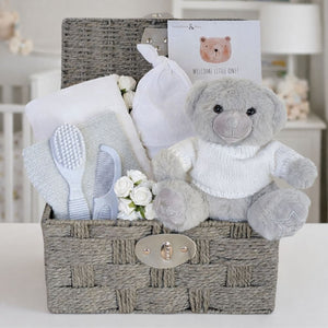 A baby basket with a teddy bear and baby essentials in a hamper. Perfect present for a new baby.