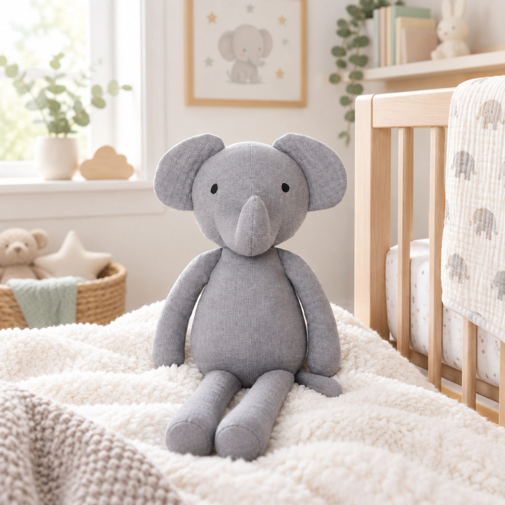 A light gray fabric elephant plush toy with black embroidered eyes and nose, standing against a plain white background.
