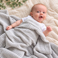 Grey cellular newborn baby blanket covering a baby