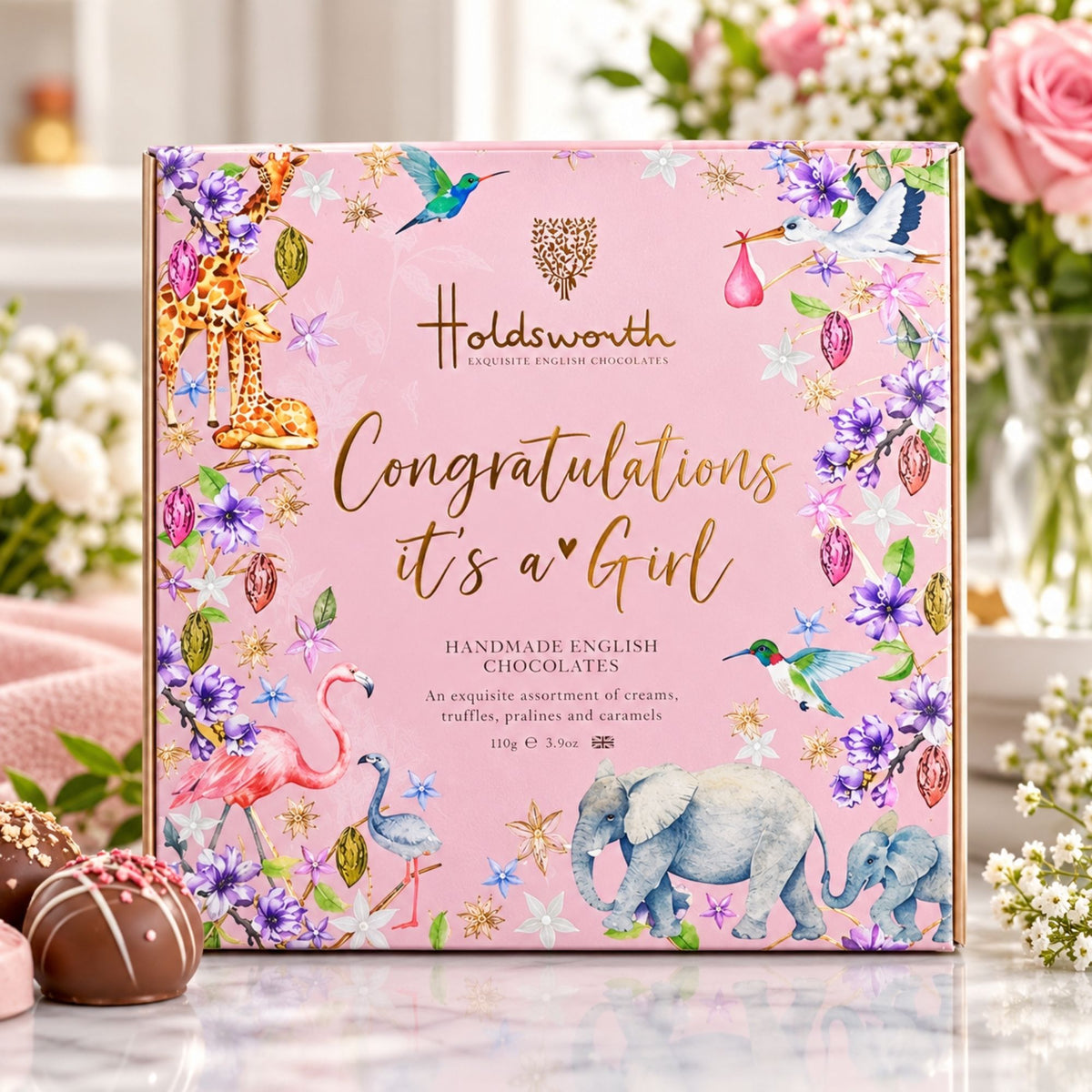 Pink chocolate box with a message on the front for a newborn baby girl ’Congratulations It's A Girl’ On a lifestyle background 