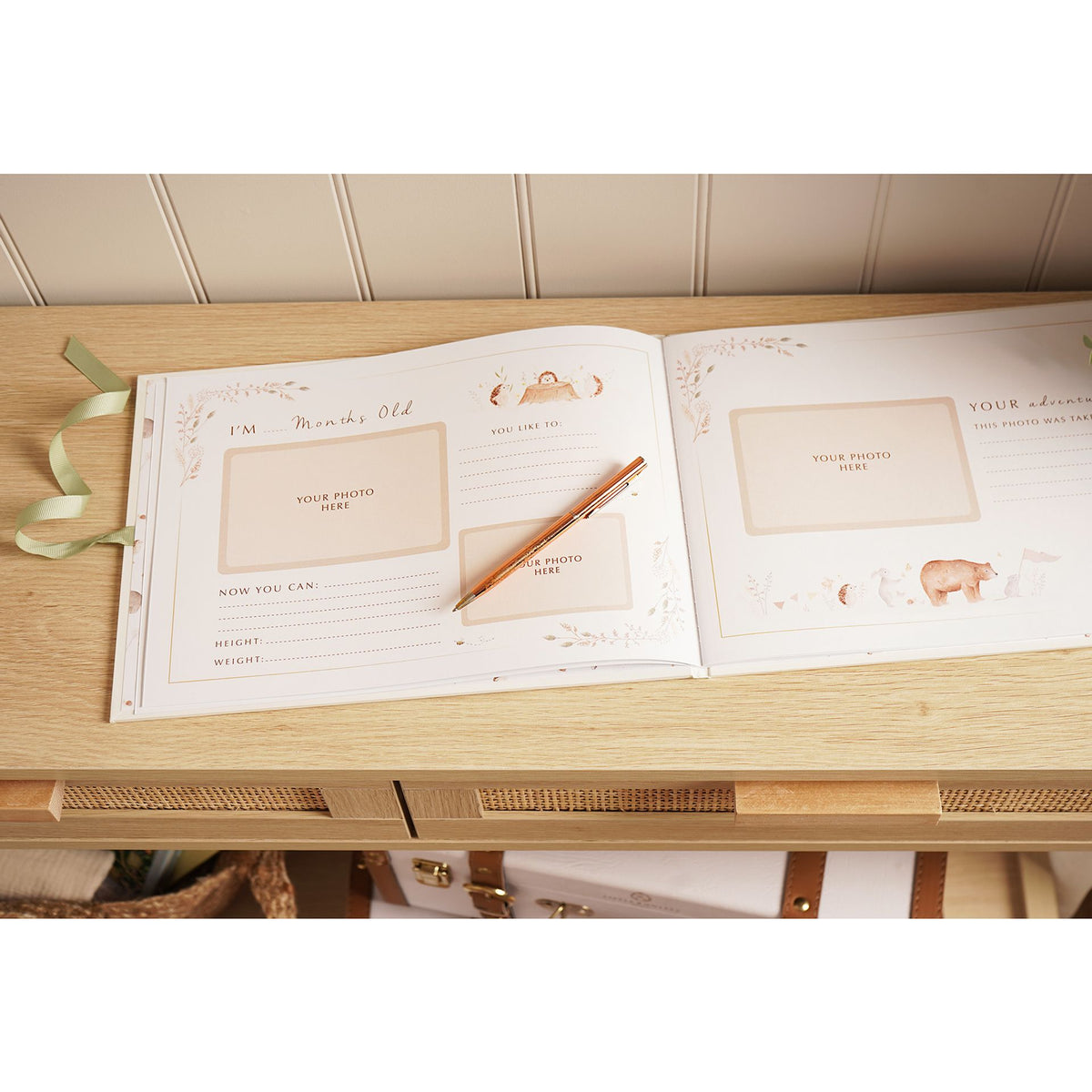 Open record book showing gratitude and photograph prompts on a wooden nursery surface.