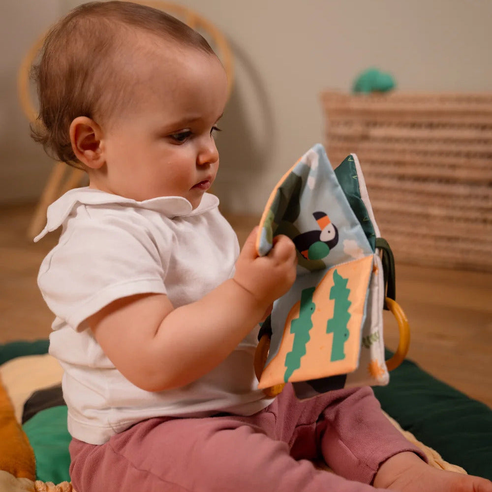 Baby holding the open Jungle Soft Baby Book with colourful animal illustrations