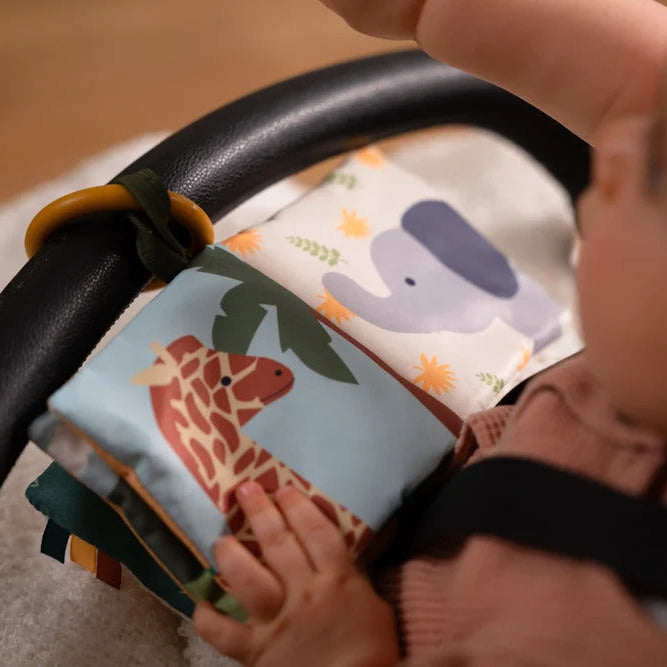 Baby exploring the Jungle Soft Baby Book attached to a stroller