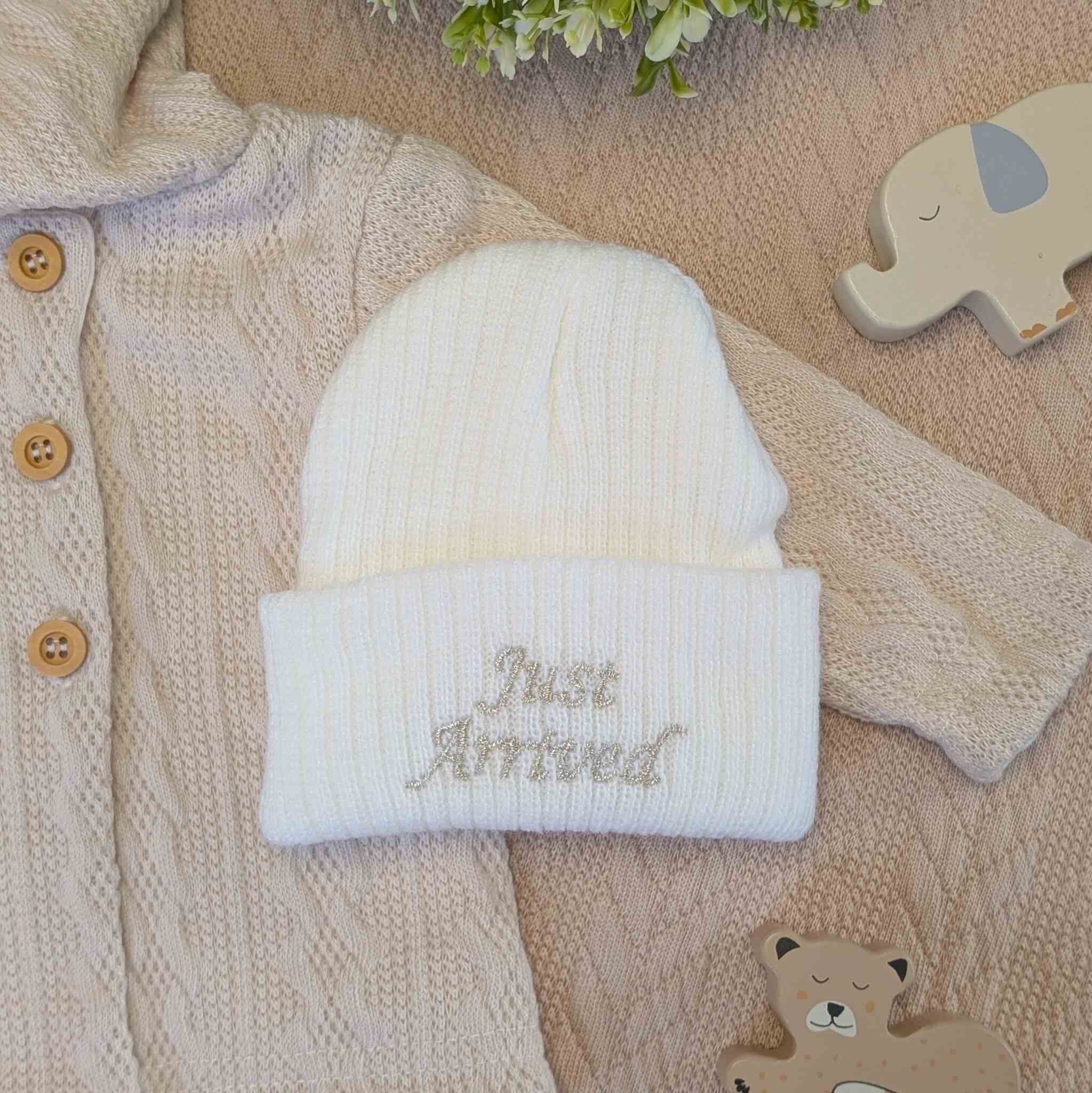 Knitted white baby beanie hat with 'just arrived' embroidered on the front