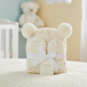White Katie Loxton hat and mittens folded together with a ribbon and product tag.