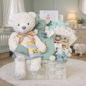 Newborn baby boy gifts basket with teddy bear, knitted items, and toys in a rope hamper basket.