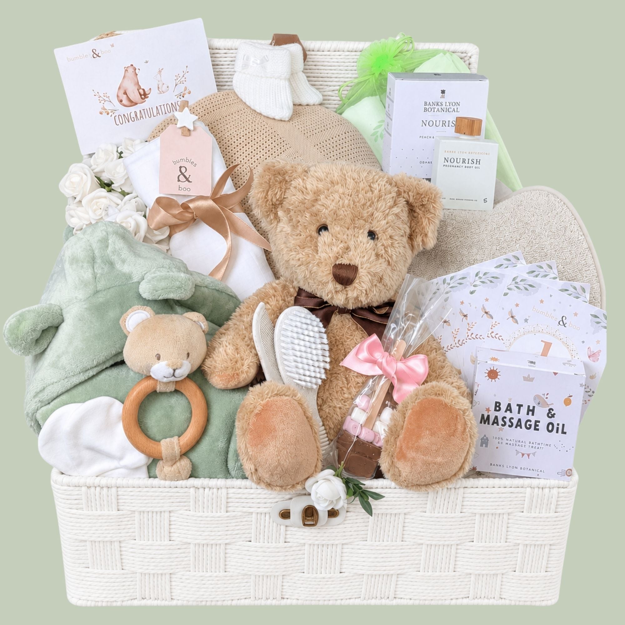 Mum to be gifts hamper with presents of pregnancy oil for expectant mums, chocolate treats and baby essentials in a woven basket