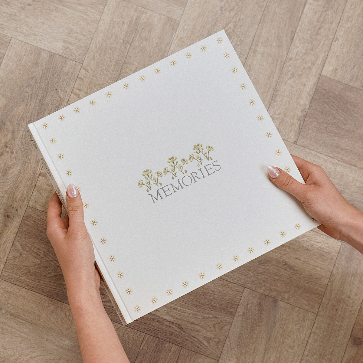 Hands holding the neutral floral MEMORIES photo album
