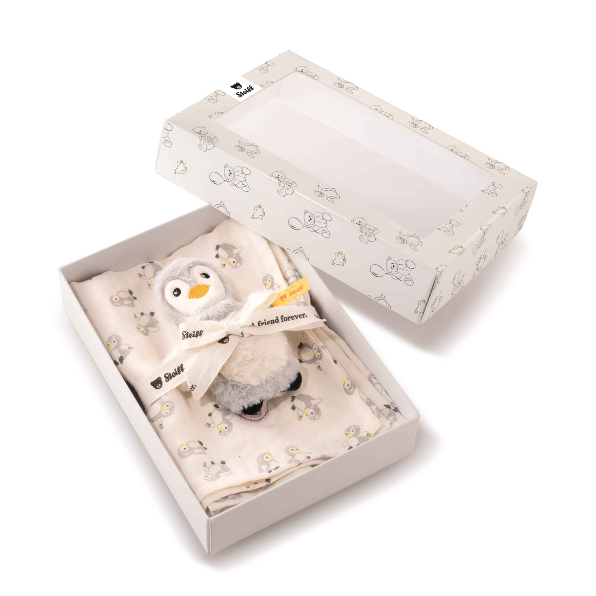 Open gift box containing the Lio penguin rattle and patterned burp cloth, with the lid placed alongside.