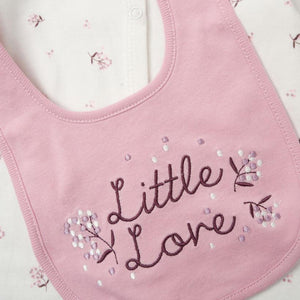 Pink bib with 'Little Love' embroidery on a matching outfit