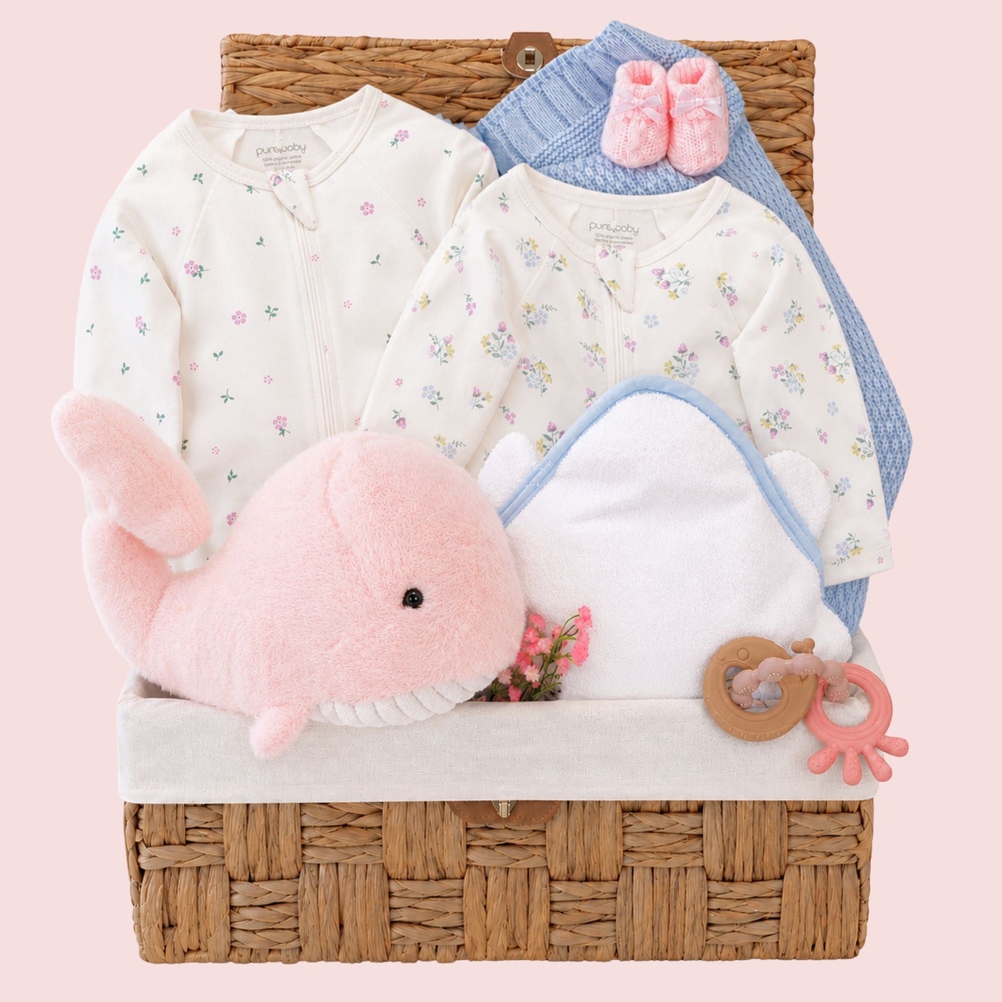 Luxury baby girl hamper basket with newborn gifts including cuddly pink whale soft toy, blue blanket and white towel.