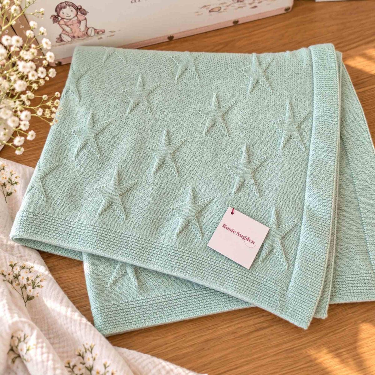 Folded mint green cashmere baby blanket showing raised star motifs and a ribbed border.