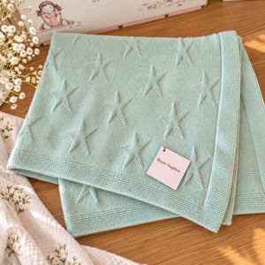Folded mint green cashmere baby blanket showing raised star motifs and a ribbed border.