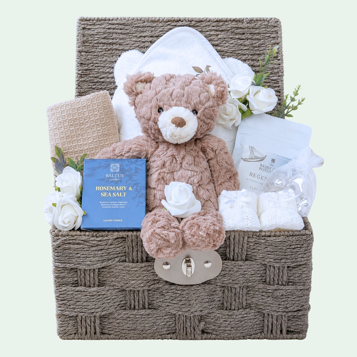 Luxury mum to be gifts in a hamper basket. Presents include teddy bear, skincare and candle.