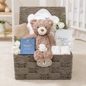 Luxury mum to be gifts in a hamper basket. Presents include teddy bear, skincare and candle.