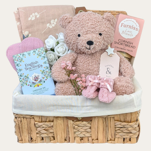 Mummy to be gift hamper with biscuits, treats for pregnancy and pink baby essentials in a wicker basket by Bumbles and Boo.
