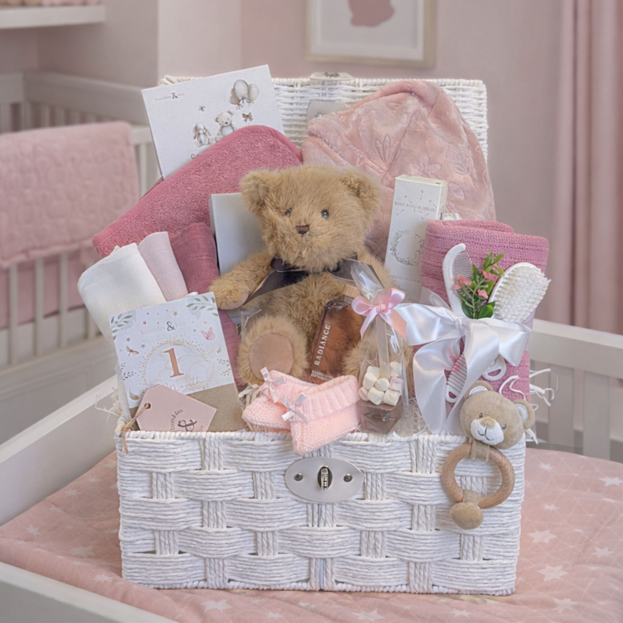 Mummy to be gifts in a white hamper basket and include teddy, towel and hooded baby bath robe in dusky pink.