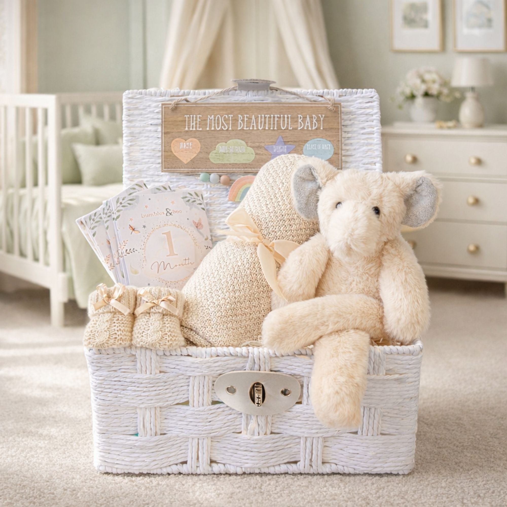 A neutral baby gifts hamper with a cream elephant theme and bamboo blanket presented in a white basket.