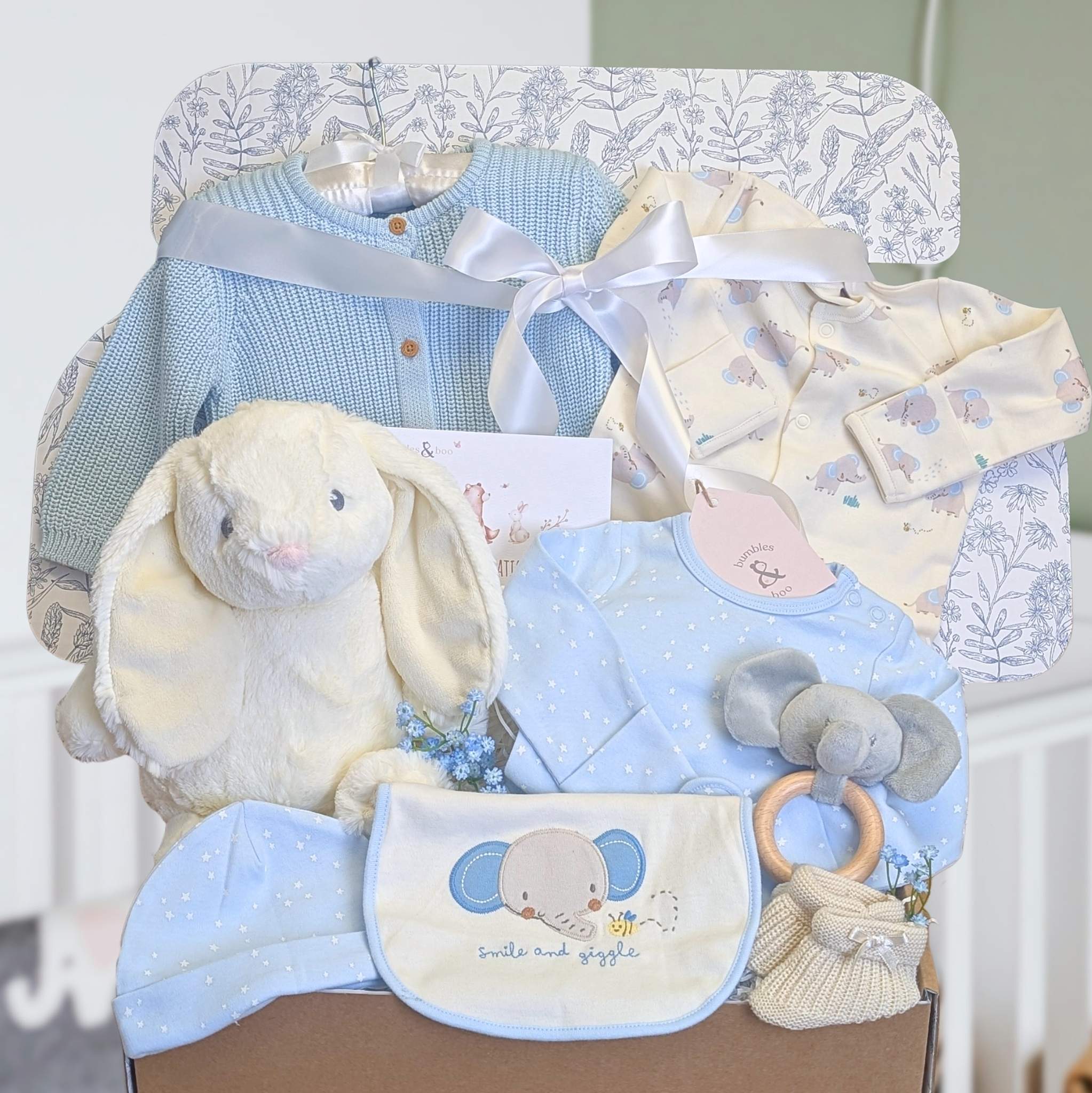 New baby boy gift box with blue and white gifts. This hamper contains a bunny soft toy and blue elephant clothes set.