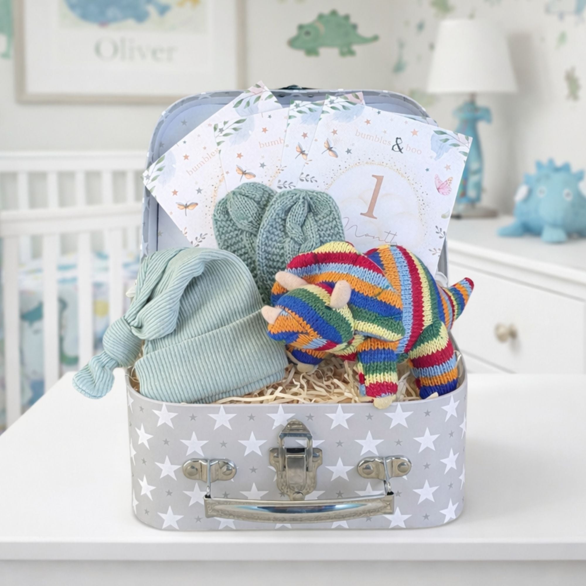 Baby boy gift set with stripy organic dinosaur baby rattle, baby hat and mittens packed inn a hamper.