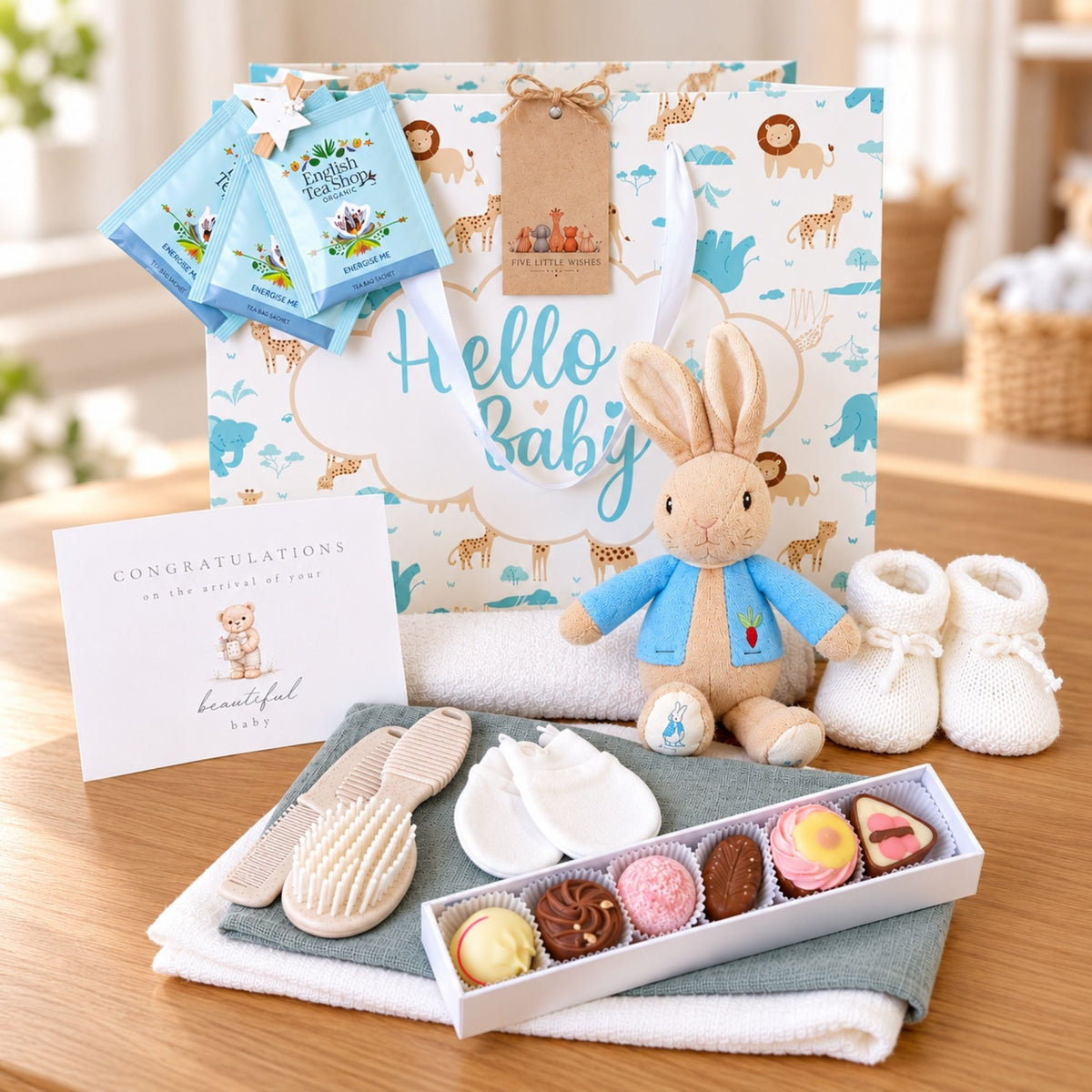 
New baby gifts hamper in a blue floral-patterned suitcase. Presents include a Peter Rabbit soft toy and treats for mum.
