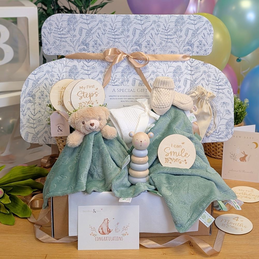 New baby gifts box with presents in this hamper including sage green teddy toy, matching comforter and wooden toy.