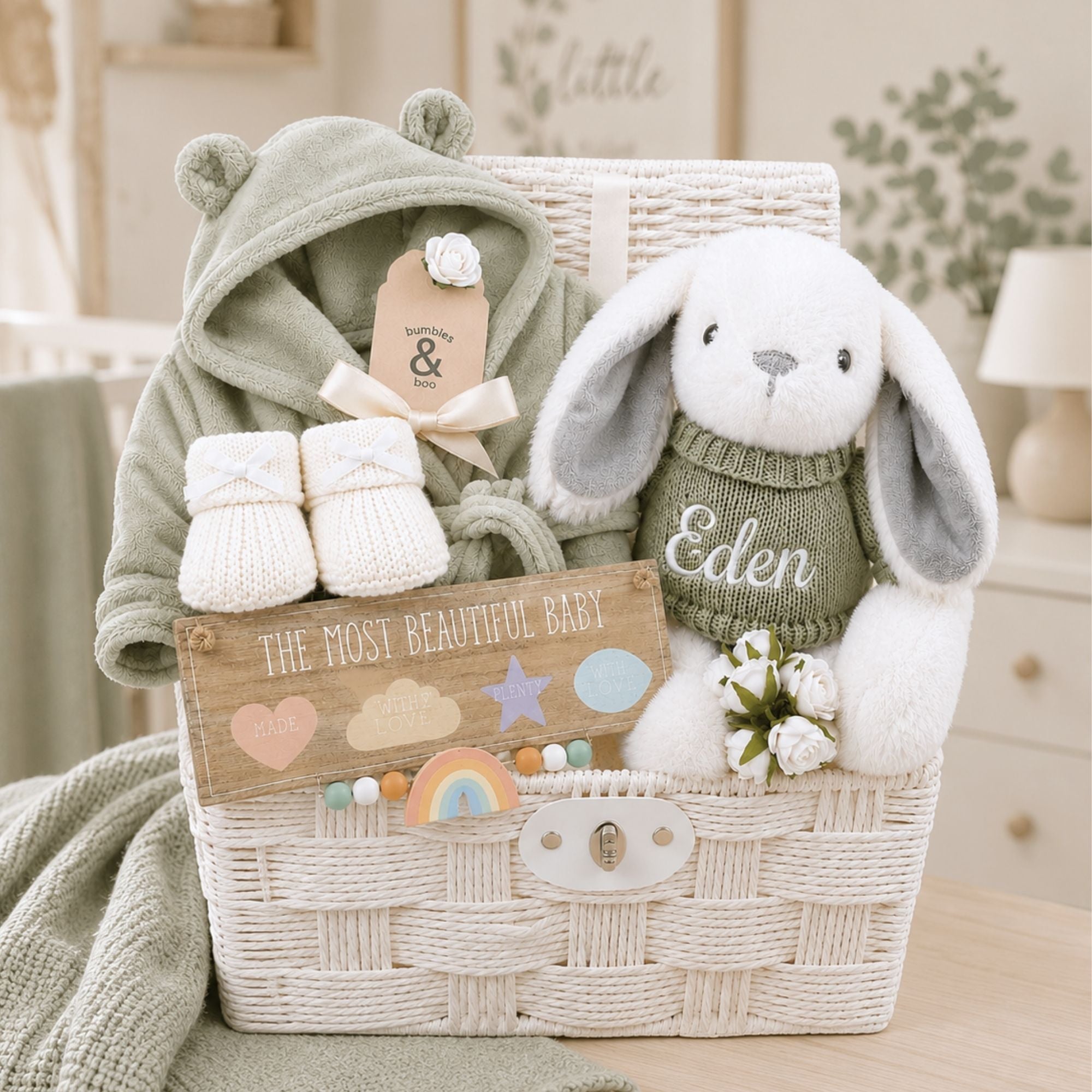 White new baby gifts hamper full of new baby gifts including bunny, booties and baby dressing gown.