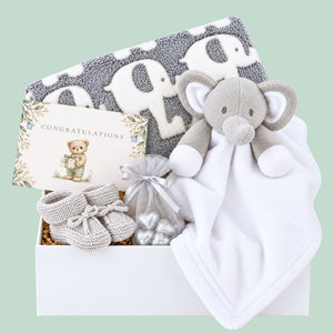 Baby hamper box with gifts including grey blanket with elephant print, white and grey baby comforter and a gift for mum.