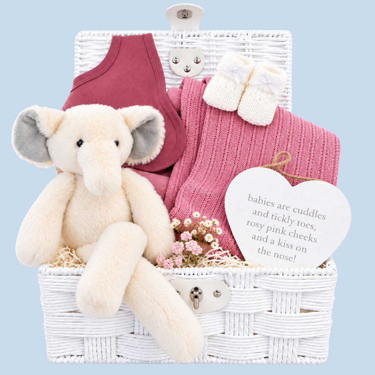 Baby girl gifts in a white hamper basket with an elephant and blossom pink cellular blanket.