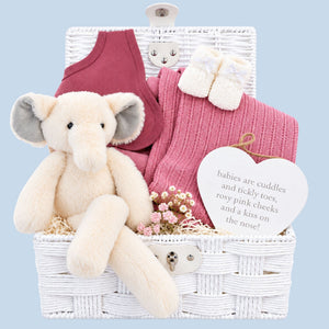 Baby girl gifts in a white hamper basket with an elephant and blossom pink cellular blanket.