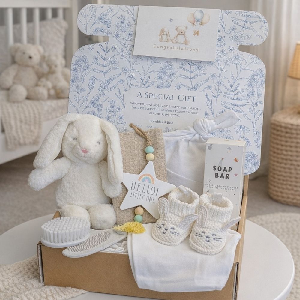 New baby gift box in pure white tones featuring a soft bunny, bunny booties, newborn hat and gentle bath-time product.