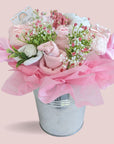 new mum gifts bouquet, with pink flowers. With gifts made of rolled up socks, mittens and booties.