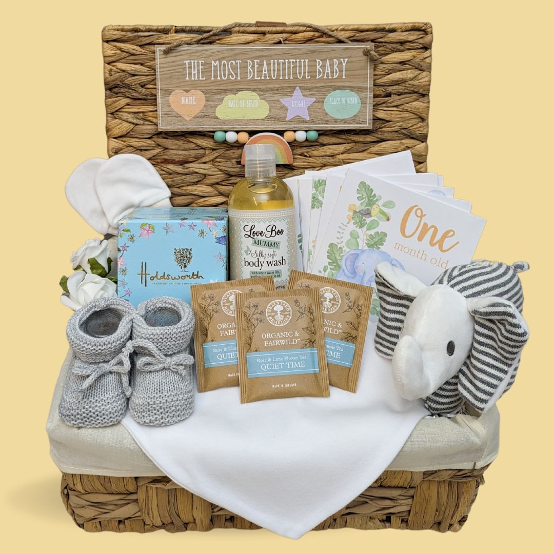 New mum gifts hamper with chocolates, organic wash, baby soft toy, baby booties and milestone cards.