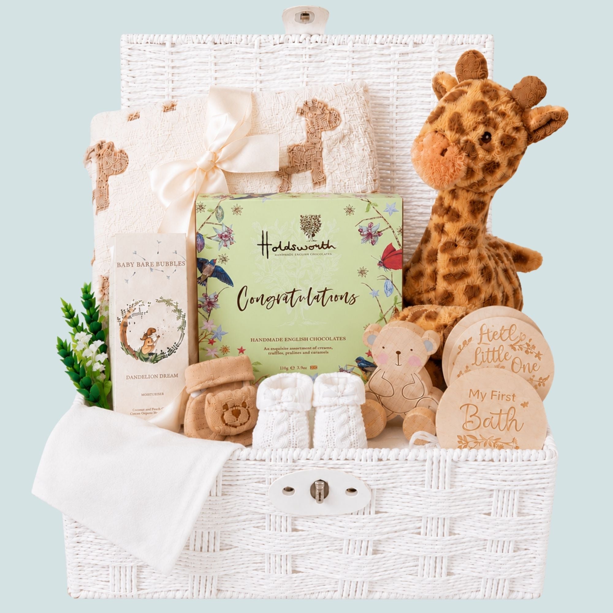 New mum hamper gifts in a white basket to include chocolates for the new parents and giraffe themed presents