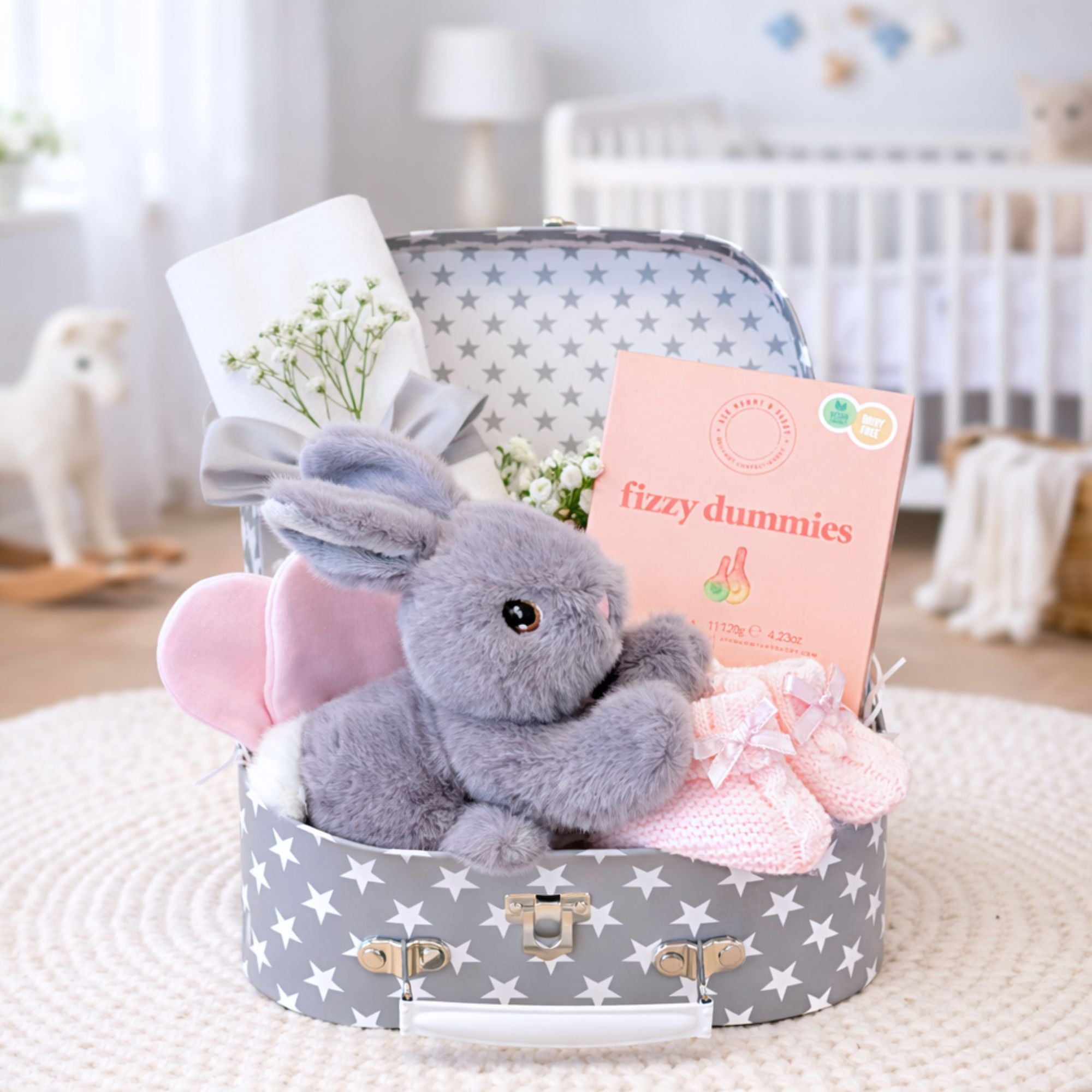 New mum presents in a luggage trunk hamper with gifts including sweets for mum and bunny rabbit soft toy for baby