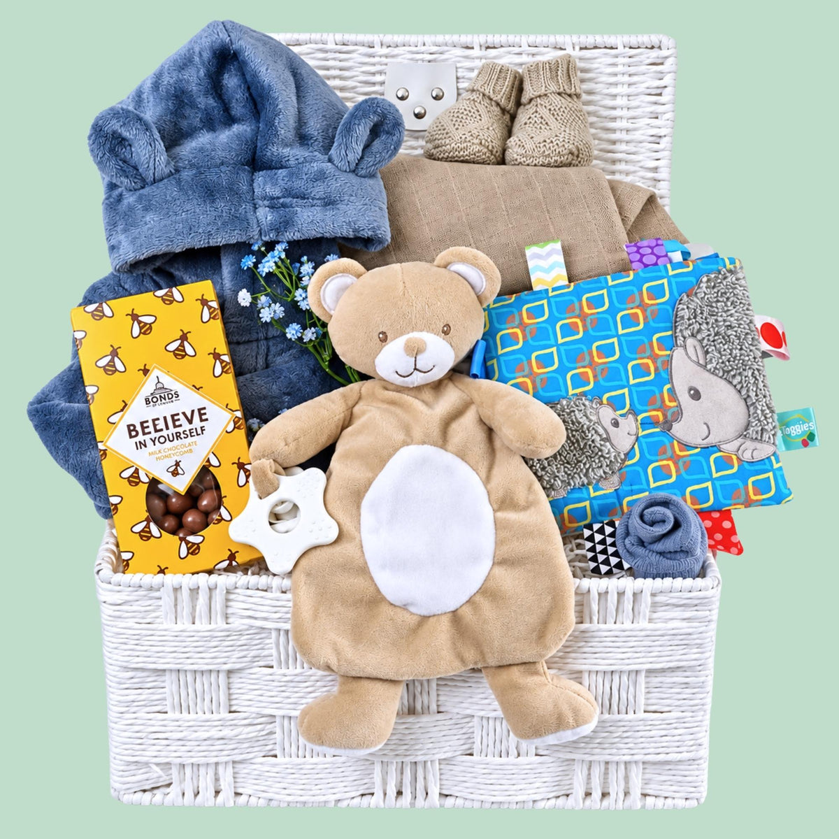 Newborn baby boy hamper basket with gifts including a blue dressing gown, taggie toy and comforter. Designed by Bumbles and Boo.
