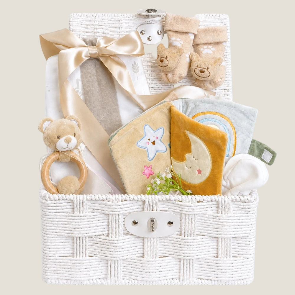 Newborn baby gifts in a hamper basket. Presents include soft book and a unisex beige theme.