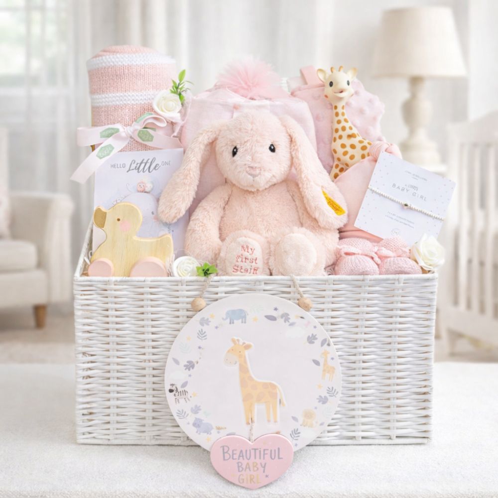 Newborn baby girl hamper basket with gifts including pink steiff bunny, blankets and baby toys in a white basket