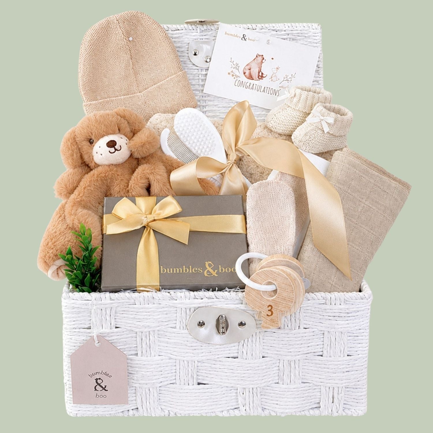 Newborn baby gifts hamper basket with teddy bear, hat, and other items in a white hamper