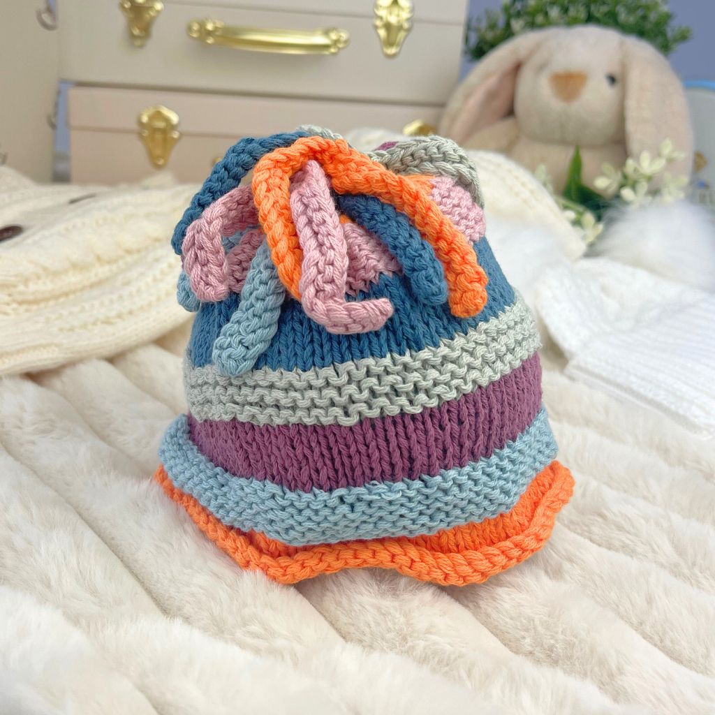 Multicoloured organic fairtrade cotton baby hat for newborns in purple, orange and blue with playful topknot detail. 