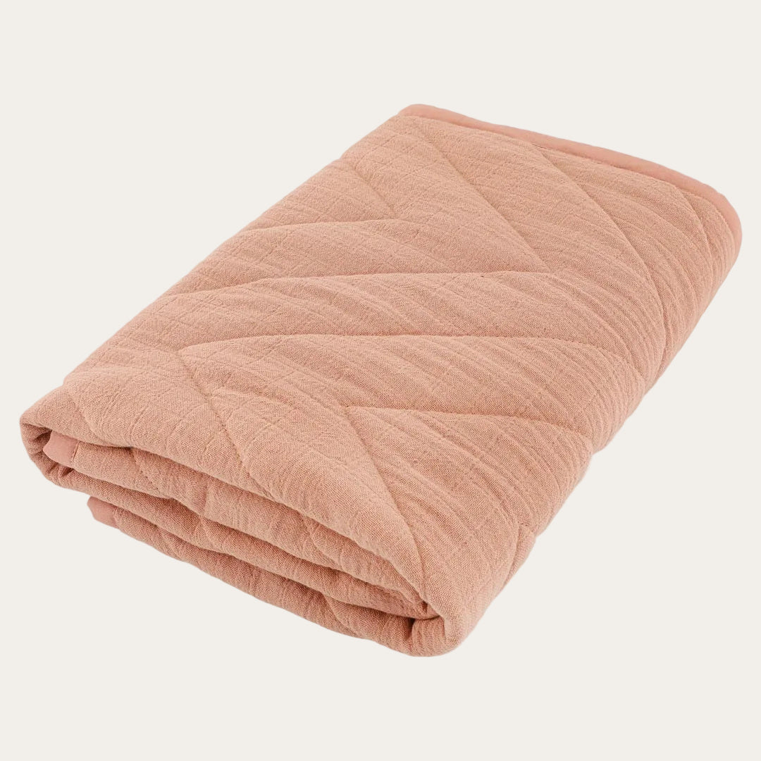 Organic cotton baby blanket in bliss coral colour, shown flat with quilted stitching detail.