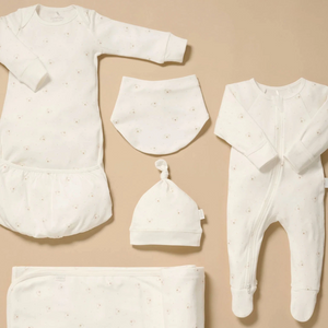 Organic newborn clothing set flat lay including growsuit, sleepsuit, blanket, hat and bib