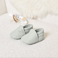Pair of pale grey baby booties with scalloped trim in soft vegan leather, neutral baby shoes for newborn baby clothes collection.