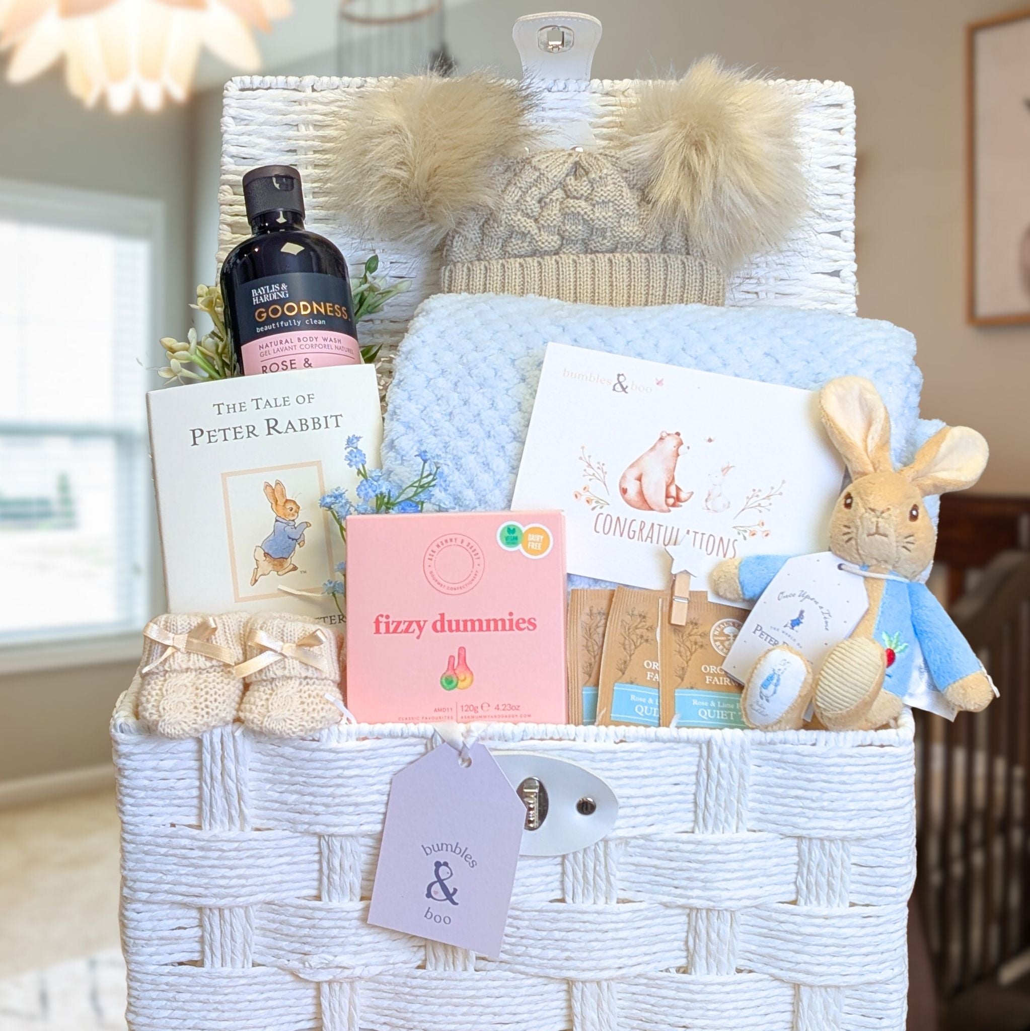 White nursery basket filled with presents for a new mum to celebrate the arrival of a baby boy.