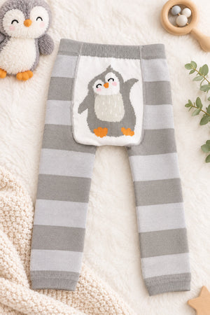 Grey striped penguin baby leggings laid flat on a cream blanket beside a penguin soft toy and wooden rattle.