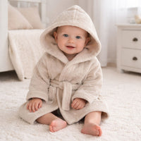 A personalised baby dressing gown with a hood in biscuit colour.