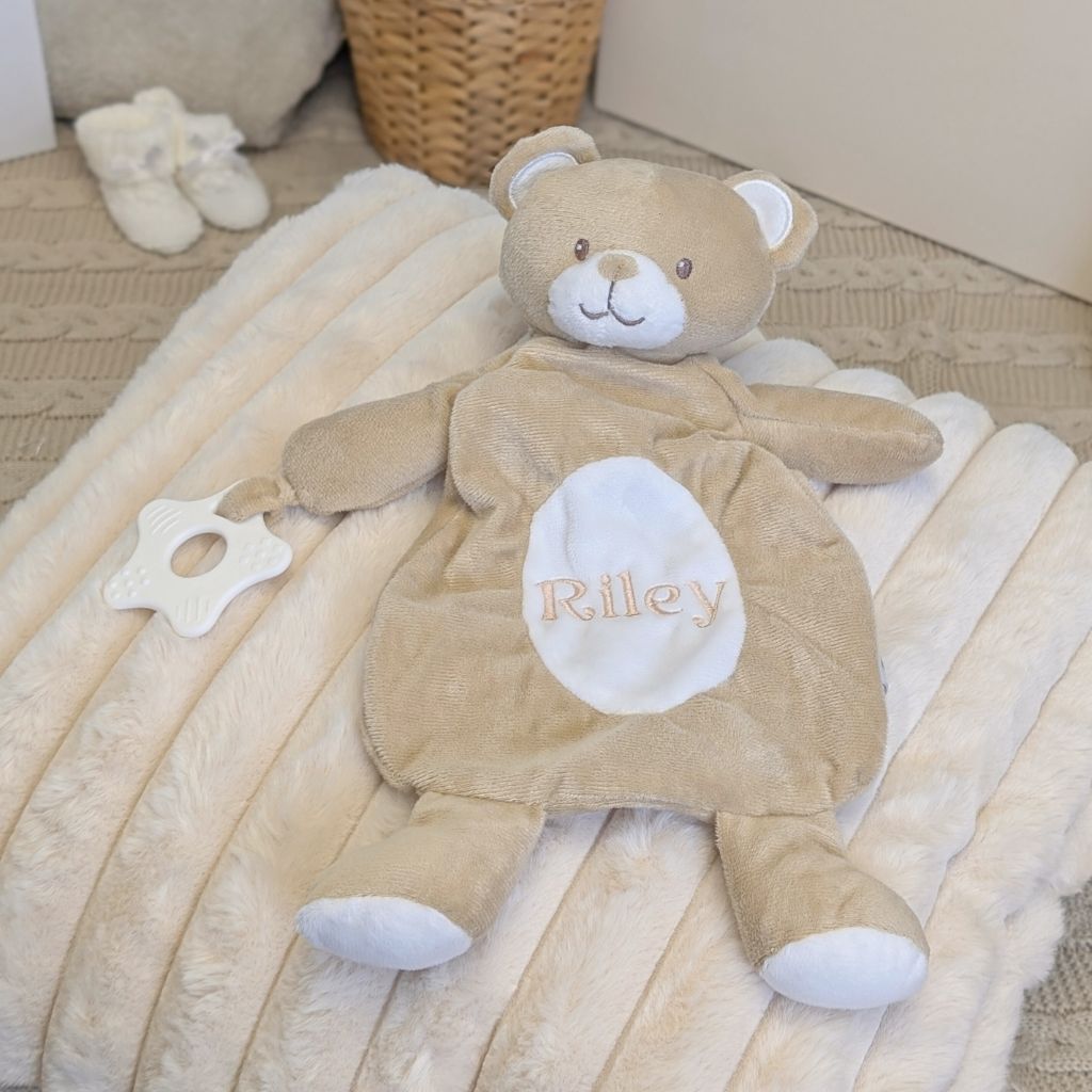 Personalised baby comforter in a beige bear design with a custom name across the tummy and teething toy attached.